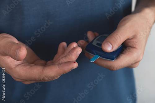 Diabetes concept. Man using digital glucometer measures level of glucose in blood. Close up