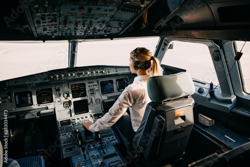 Woman pilot sitting in aircraft cockpit, flying the plane. photo