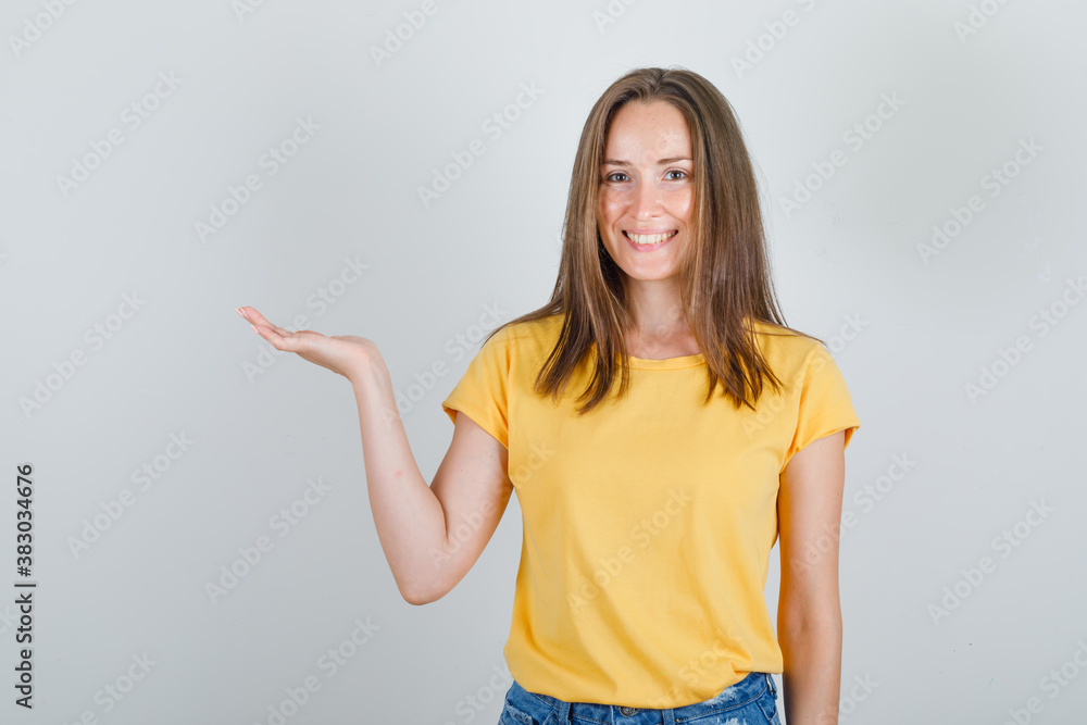 Young woman keeping raised palm in t-shirt, shorts and looking cheerful. front view. Young woman keeping raised palm in t-shirt, shorts and looking cheerful. front view.