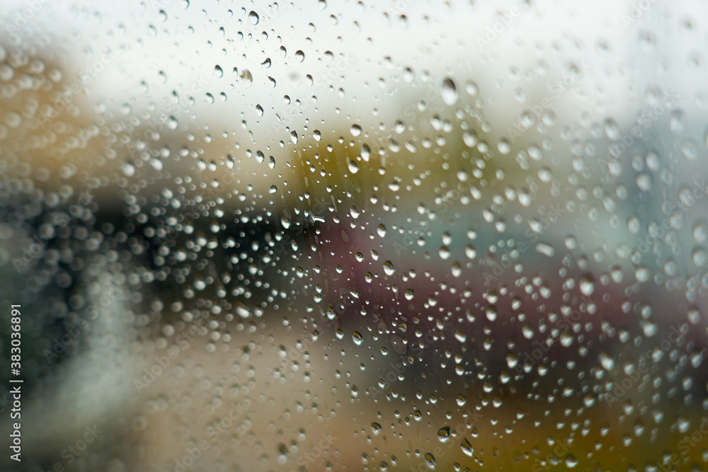 Raindrops on the glass with blurred car on the background. Selective focus.