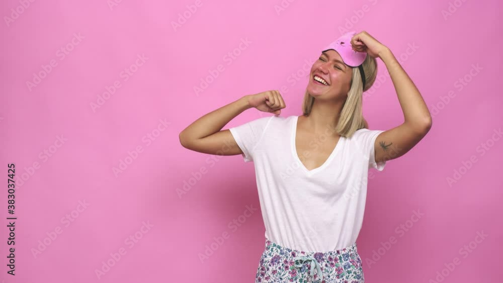 Young cute woman wearing pajama raising fist after a victory, winner concept Young cute woman wearing pajama raising fist after a victory, winner concept