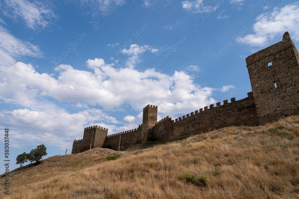 ruins of the fortress, The old defensive wall of the fortress, against the blue sky and yellow grass