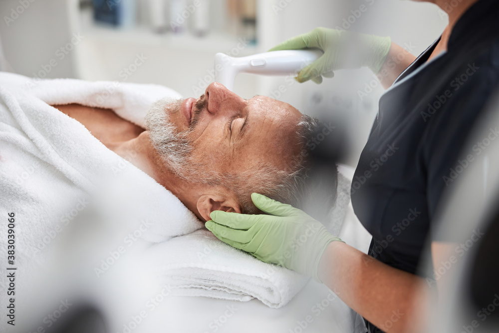 Aging man looking chilled at a skincare treatment session Aging man looking chilled at a skincare treatment session