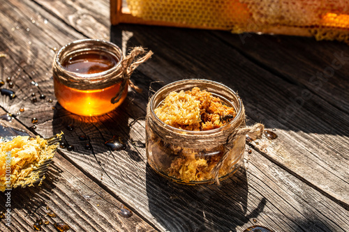 Beekeeping concept. jar of fresh honey in a glass jar, beekeeping tools outside. frame with bees wax structure full of fresh bee honey in honeycombs photo