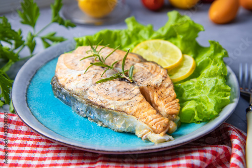Baked salmon steak with lemon in a plate on the table