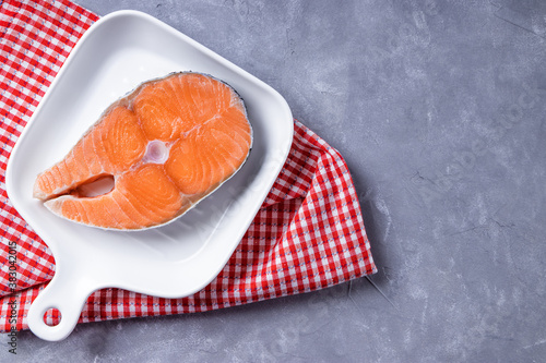  Raw salmon steak on a white plate, top view. Red fish on a concrete background, free space for text