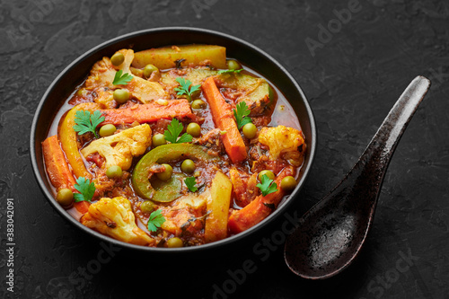 Veg Kolhapuri in black bowl on dark slate table top. Indian vegetable curry dish. Vegetarian asian food and meal. photo