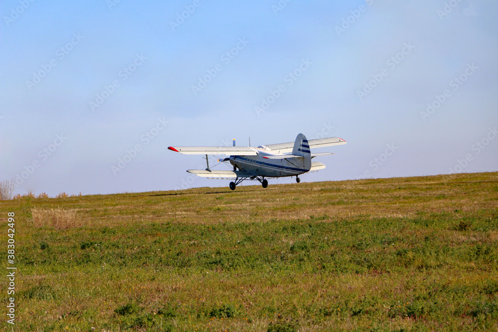 small biplane, an agricultural maize plane, with a special diffuser for field fertilizers and pesticides, picks up speed and takes off over the autumn field. small biplane, an agricultural maize plane, with a special diffuser for field fertilizers and pesticides, picks up speed and takes off over the autumn field.