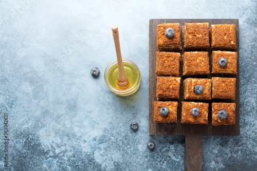 Pieces of gourmet cake decorated with blueberries. Top view, concrete background. Sweet honey cake on cutting board