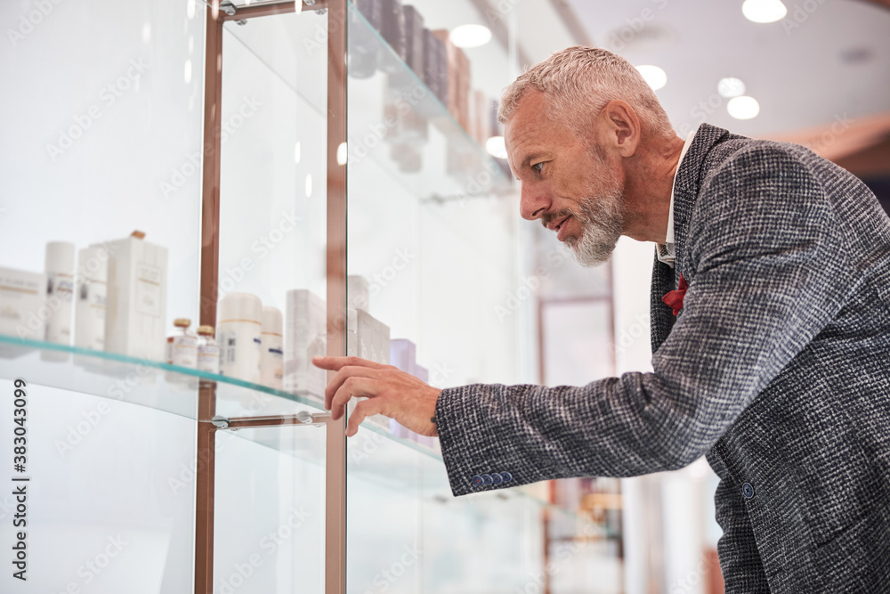 Focused aged man choosing cosmetics at a shop Focused aged man choosing cosmetics at a shop
