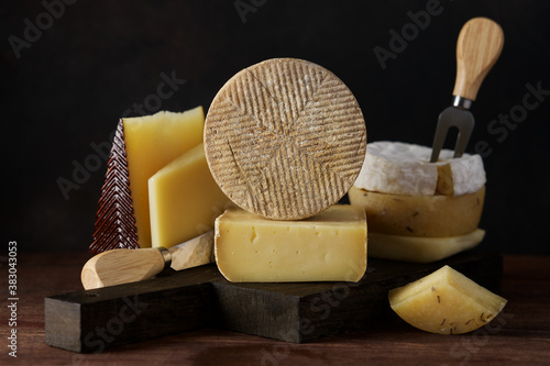 Set of hard cheeses gruyere and manchego on cutting board on dark background photo