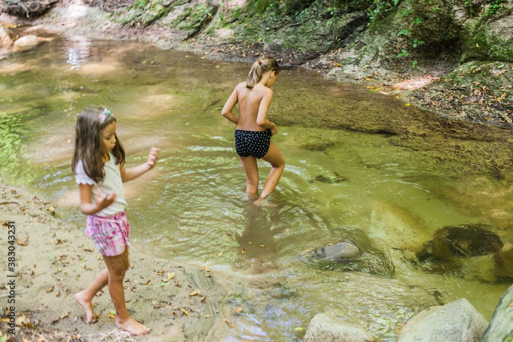 Fototapeta premium Happy children have fun by mountain creek at summer forest. Natural day light. Adventure