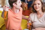 selective focus of young man and woman holding bottles of beer during party