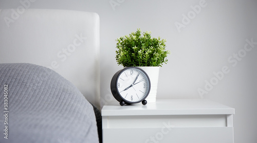 Vászonkép good morning concept - alarm clock and houseplant on bedside table