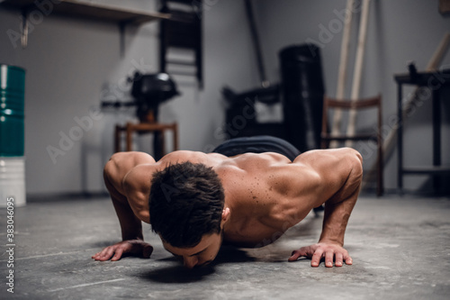 a muscular sportsman does push-UPS from the floor in the gym