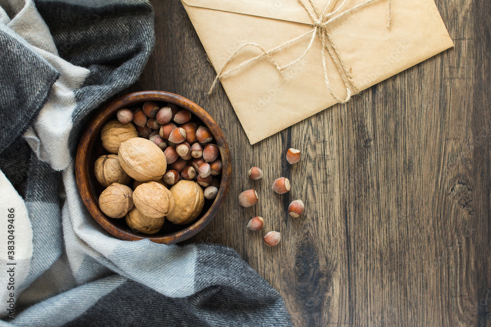 Fototapeta premium Nuts hazelnuts and walnuts in a cup, letter, plaid. Wooden background. Autumn composition.