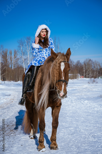 Beautiful young woman riding a horse on a Sunny winter day