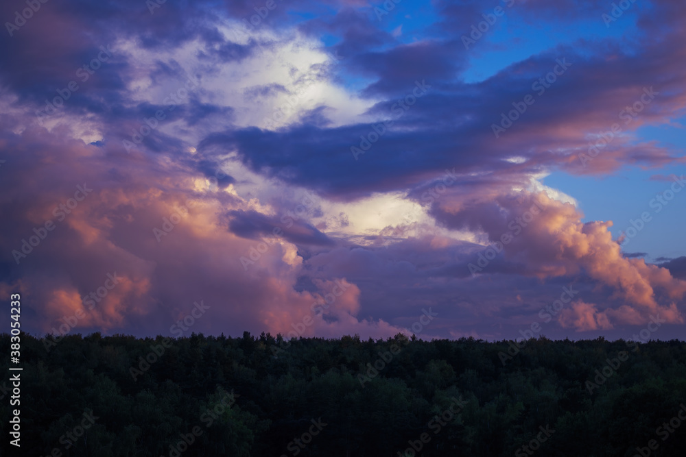 There are dramatic clouds in the dark sky as the sun sets. The sky is dominated by fuchsia, pink.