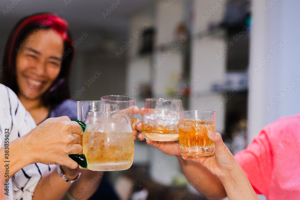 Group of friends toasting glasses whisky in the party at family dinner.