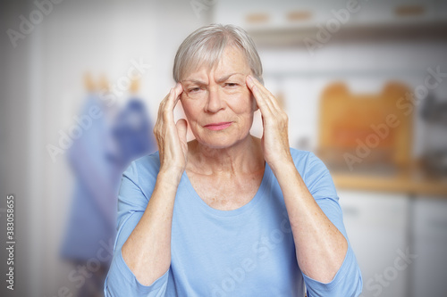 Hypertension concept: elderly woman with untreated high blood pressure suffering from an acute headache. photo
