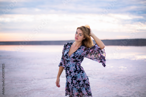 beautiful girl in a flower dress on a salty pink still water lake at a vanilla sunset