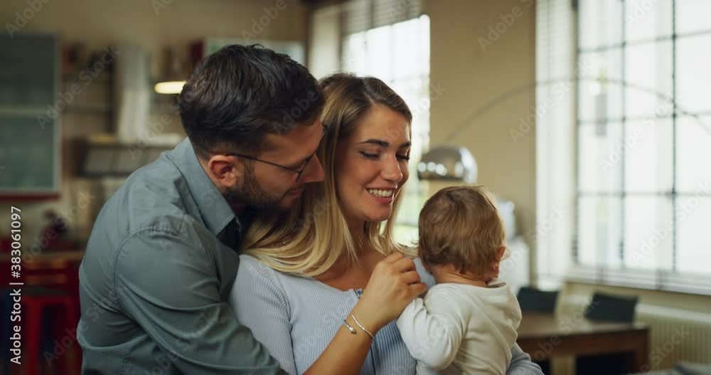 Authentic shot of a young happy family with toddler baby boy are smiling in camera in a kitchen at home. Authentic shot of a young happy family with toddler baby boy are smiling in camera in a kitchen at home.