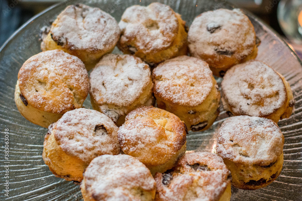 a plate of raisin scones dusted with icing sugar on display
