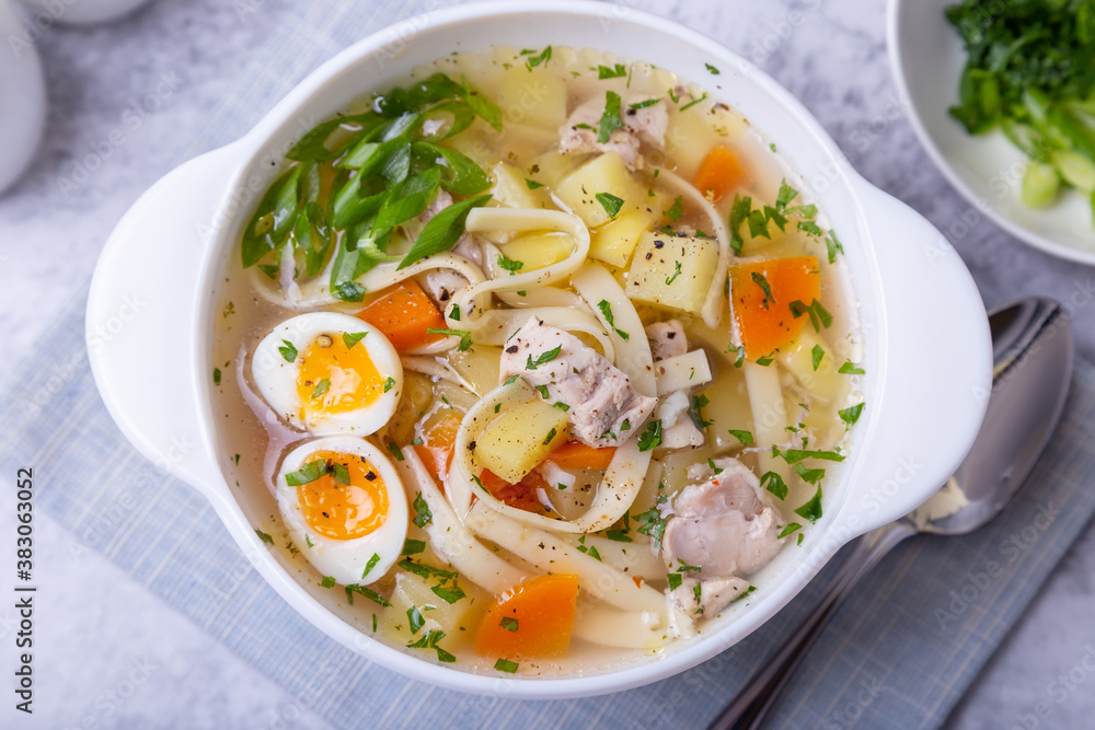 Soup with chicken, noodles, potatoes, quail eggs and carrots. Seasoned with onions and parsley. Close-up. Soup with chicken, noodles, potatoes, quail eggs and carrots. Seasoned with onions and parsley. Close-up.