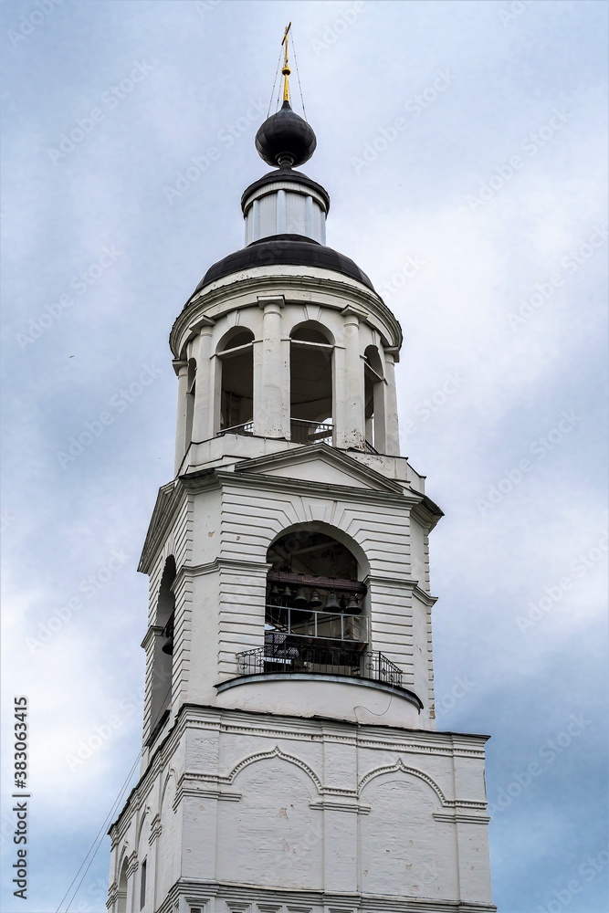 Bell tower of the old church against the sky with clouds.