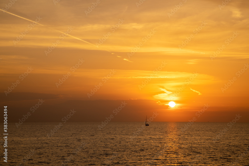 Segelboot auf dem Ozean vor der untergehenden Sonne