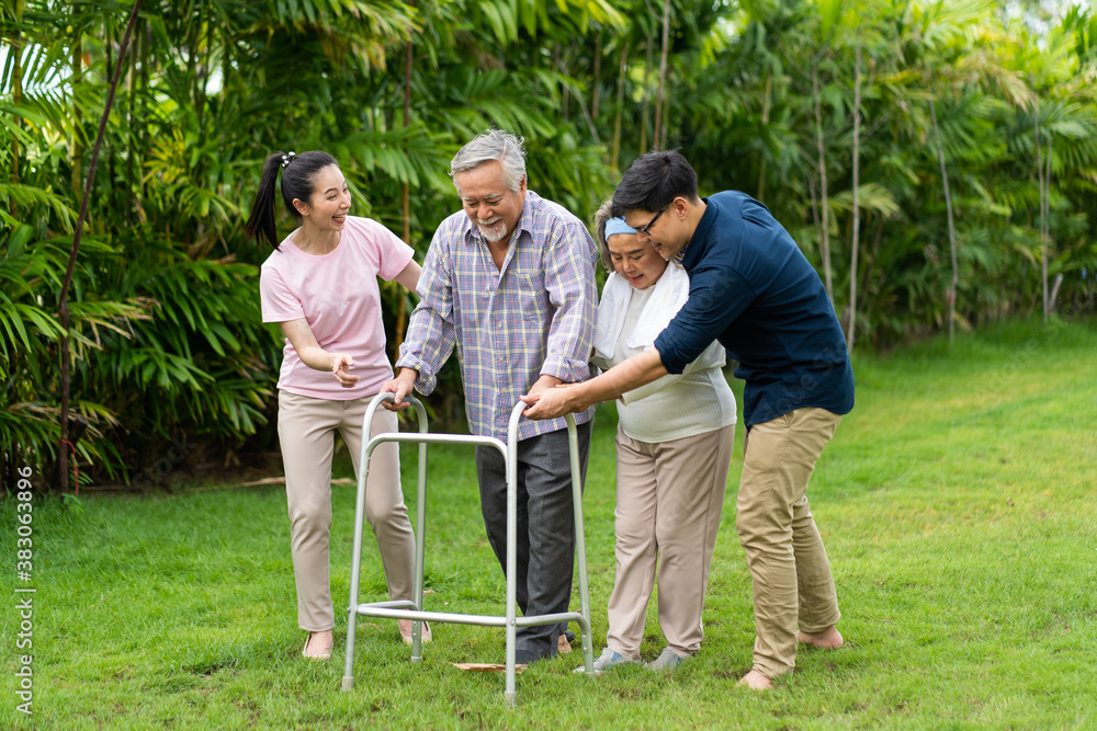 A family is trying to help Dad to walk because father is paralysed on lawn at home. paralysis and walking crutch concept. A family is trying to help Dad to walk because father is paralysed on lawn at home. paralysis and walking crutch concept.