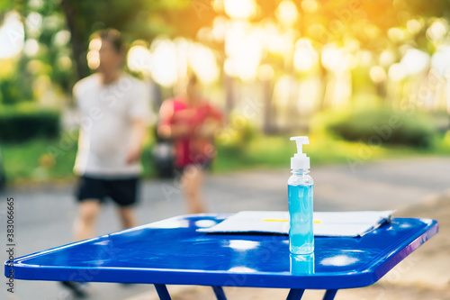 Blue alcohol gel bottle and a register book on the table for athletes to prevent Corona Virus (COVID -19) infection and spread before exercising in public park. New normal lifestyle. Selective focus
