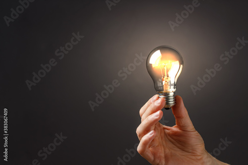 A man holds a luminous bulb in his hand. Concept idea. Copy space.