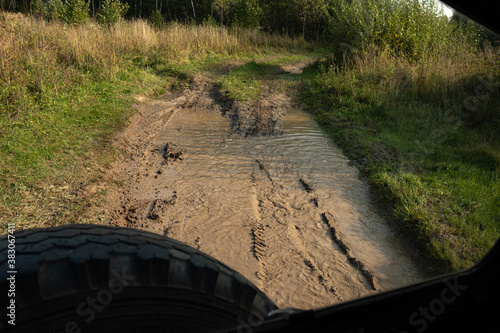 Off-road view - the ruts of the road full of mud and water, from the body of an off-road vehicle.