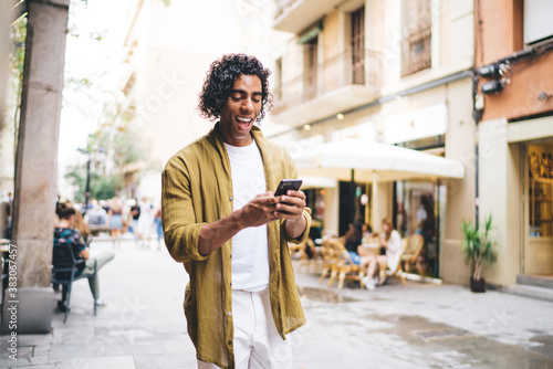 Cheerful young man using smartphone on street