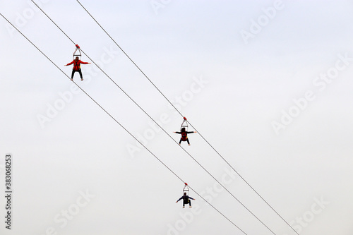 People having fun on the zipline on sky background