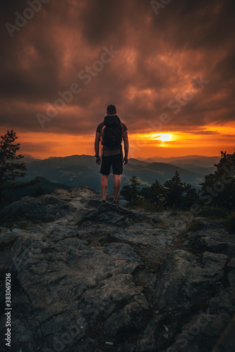 Hiker with backpack standing on mountain and enjoying sunset © Maximilian