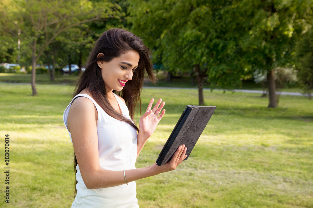 Indian student girl communicate using modern means of communication. Portrait of a woman with a tablet in her hands outdoors. Online dating Indian student girl communicate using modern means of communication. Portrait of a woman with a tablet in her hands outdoors. Online dating
