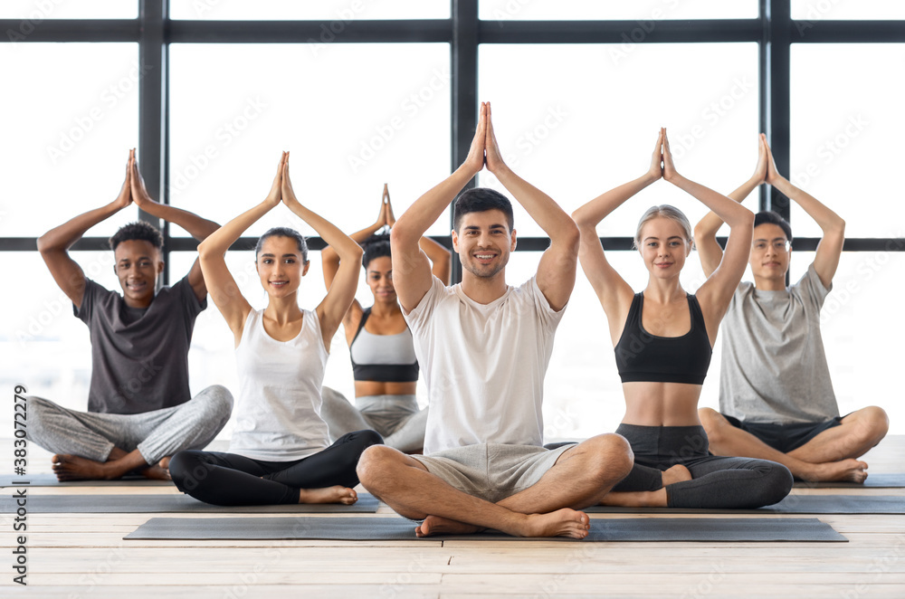 Naklejka premium Wellbeing Concept. Happy multicultural people practicing group yoga in modern studio