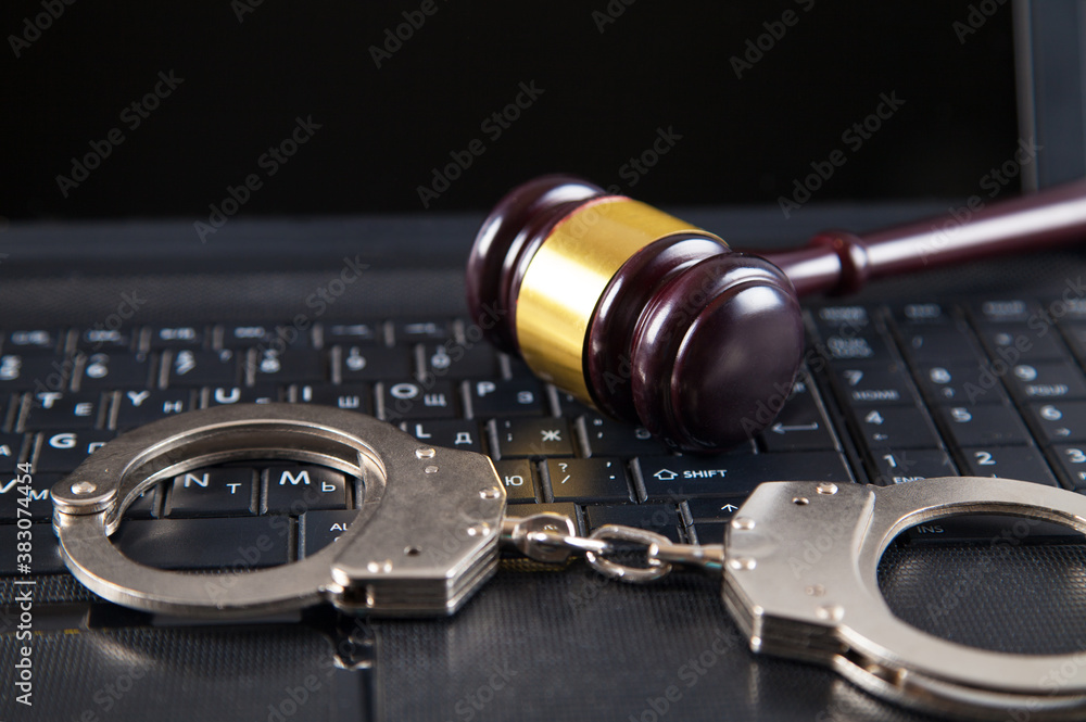 Judge gavel, police handcuffs and computer keyboard.