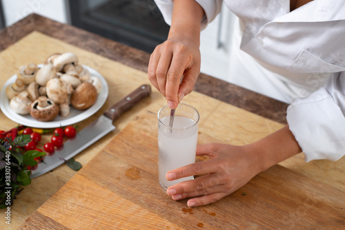 The cook mixes the yeast with a spoon in a glass of water.