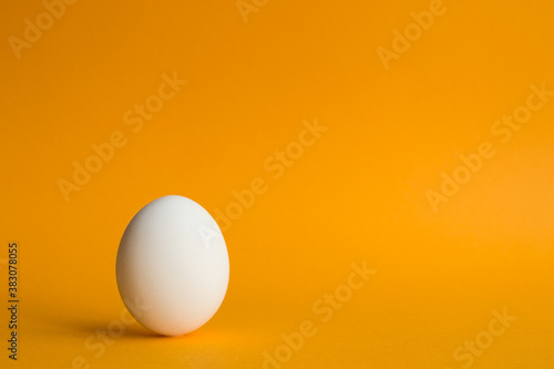 White hen's egg on orange background to commemorate world egg day partial focus