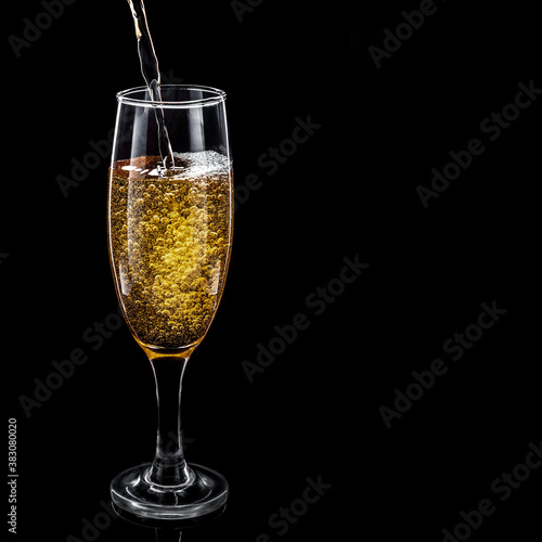 Champagne with bubbles in a glass on a black background. Place for text