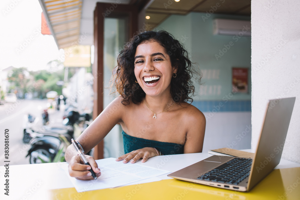 Cheerful lady filling in paper form at desk with laptop Cheerful lady filling in paper form at desk with laptop