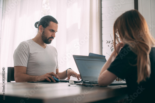 A man and a woman are working at a table at home