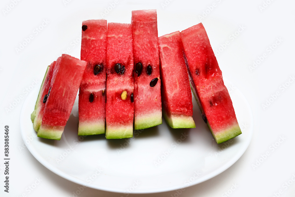 triangular pieces of watermelon on the background lie on a white plate on the background of a white table. harvest concept, vitamins tasty and healthy food. triangular pieces of watermelon on the background lie on a white plate on the background of a white table. harvest concept, vitamins tasty and healthy food.