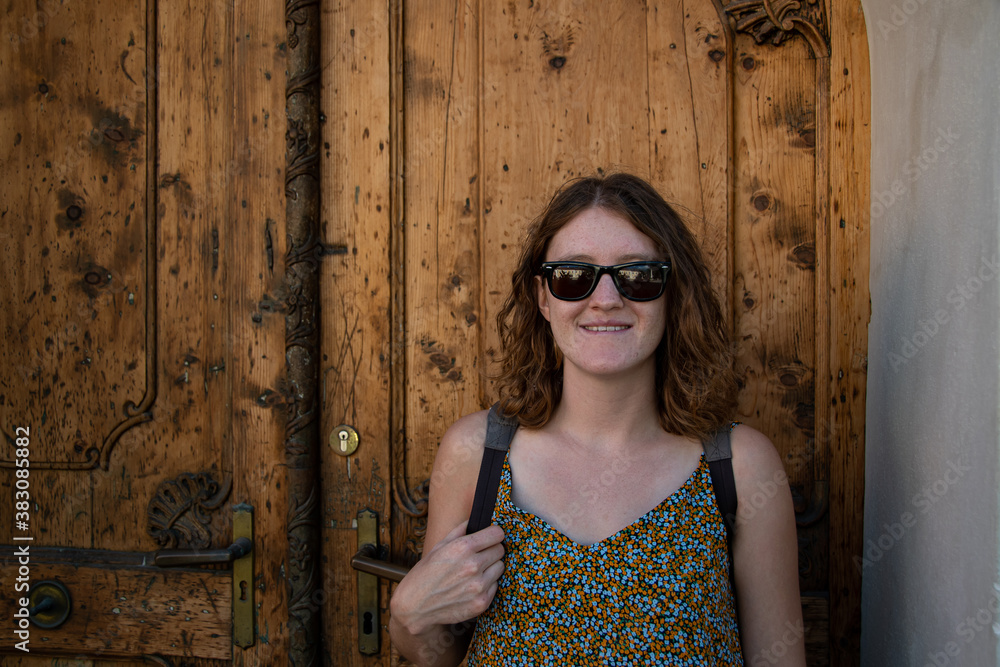 Fototapeta premium Young attractive woman in sunglasses in front of an old wooden door