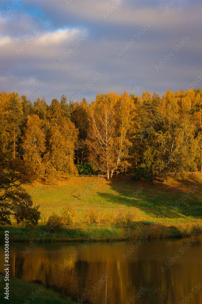Autumn sunny park Landscape. Autumn Trees and River whith a cloudy blue Sky.