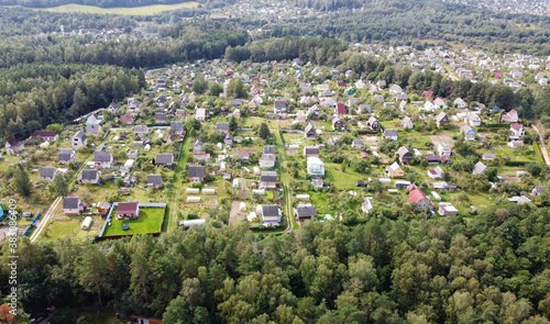 Beautiful top view of suburban cottages with park and forest. Rural landscape with roofs of small houses and villages