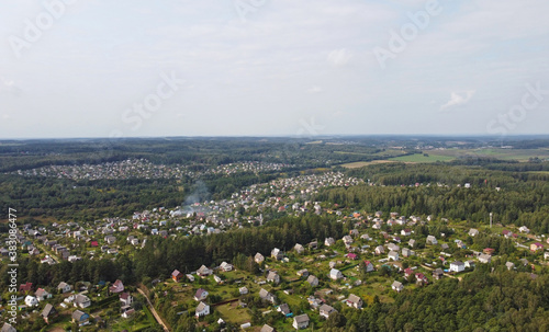 Beautiful top view of suburban cottages with park and forest. Rural landscape with roofs of small houses and villages